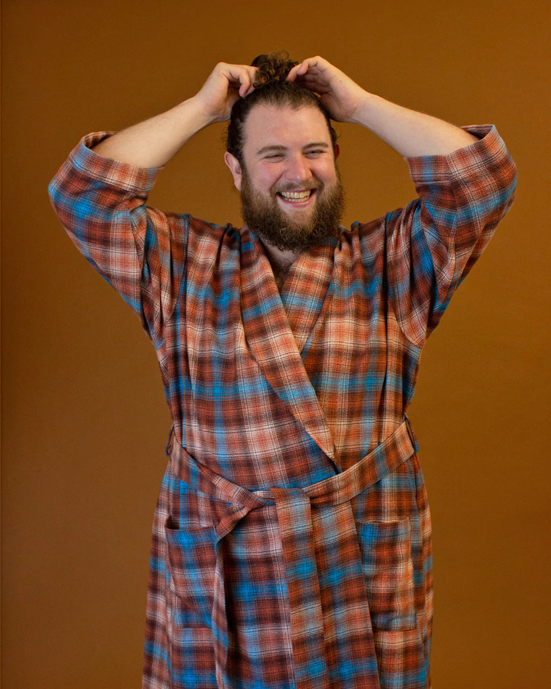 Front detail of a person in a flannel plaid bath robe against a pumpkin colored backdrop