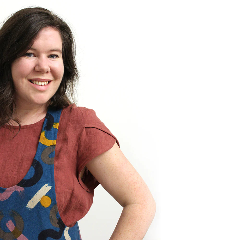 A woman wearing a rust colored top with short petal sleeves.