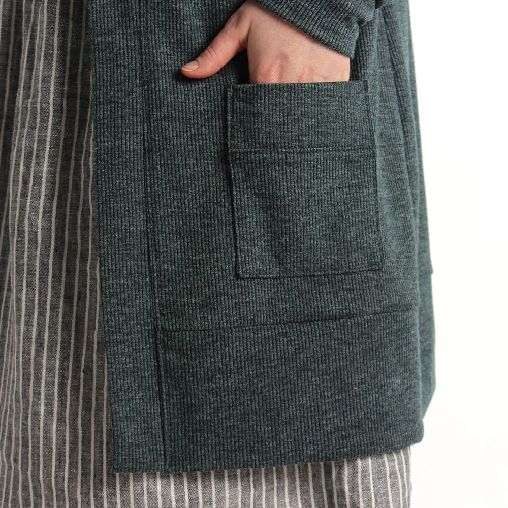 detail of a person with a hand in a pocket of a blackwood cardigan in view a