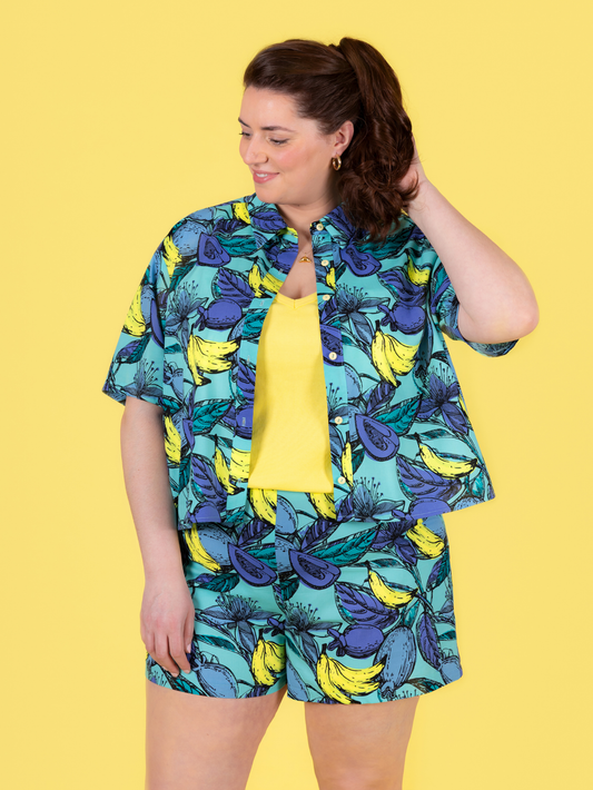 Woman wearing a colorful shirt and shorts set with a yellow background