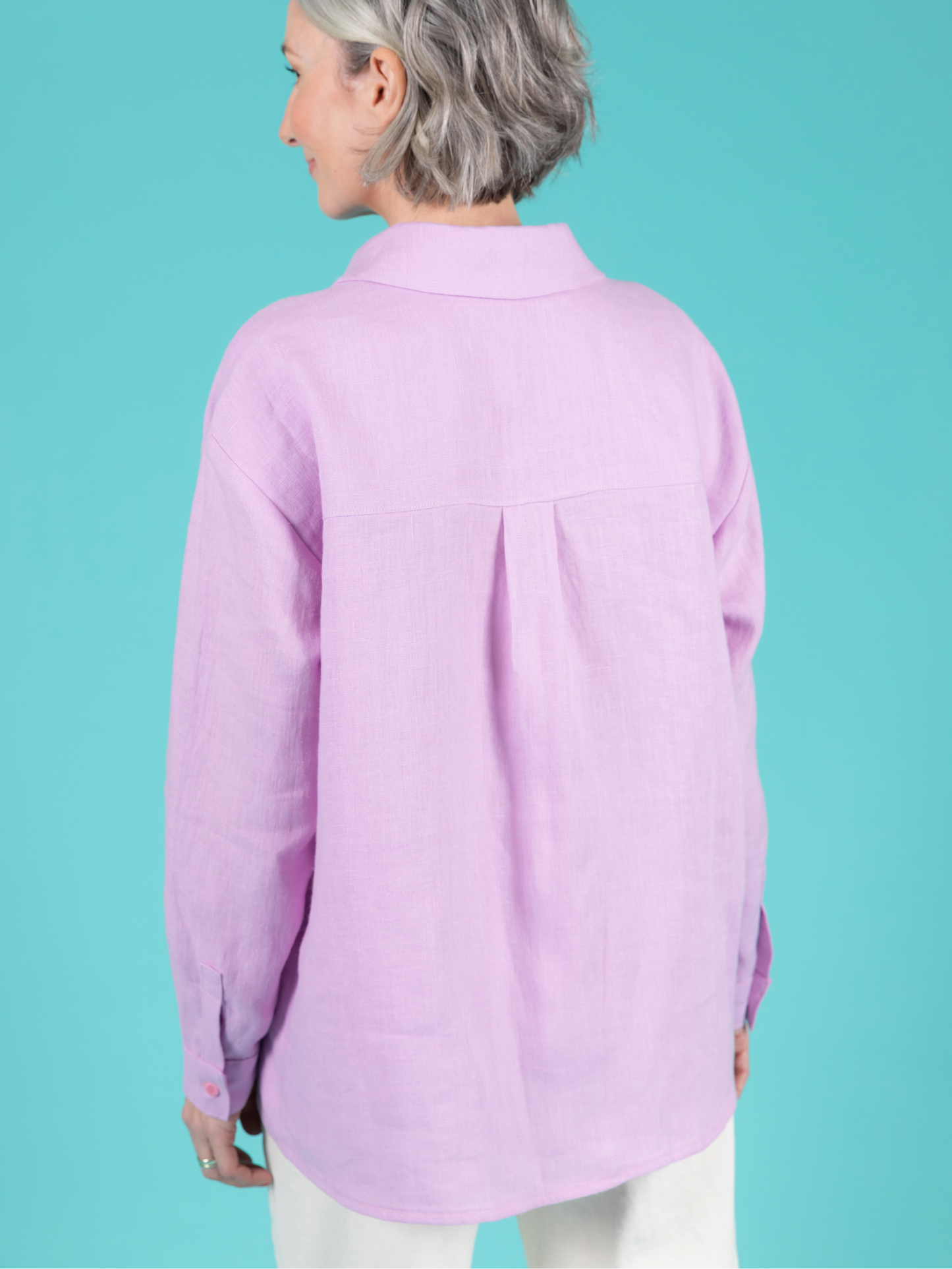 Person wearing a light purple shirt against a teal background