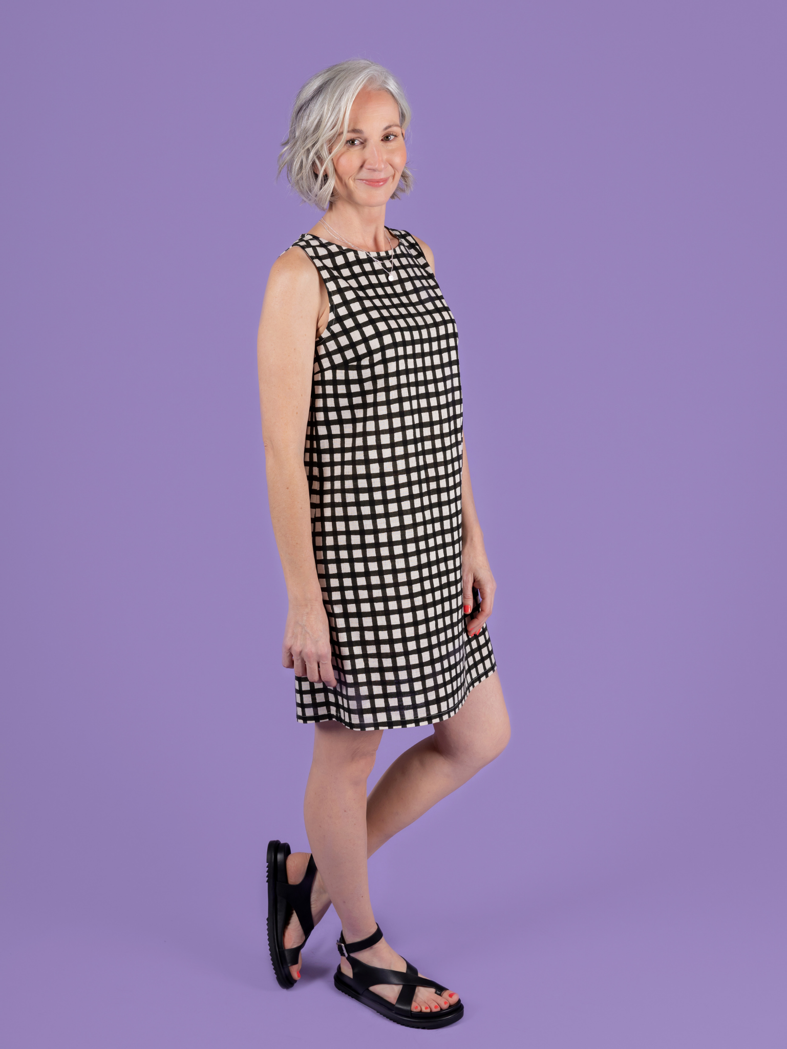Woman wearing a black and white checkered dress against a purple background