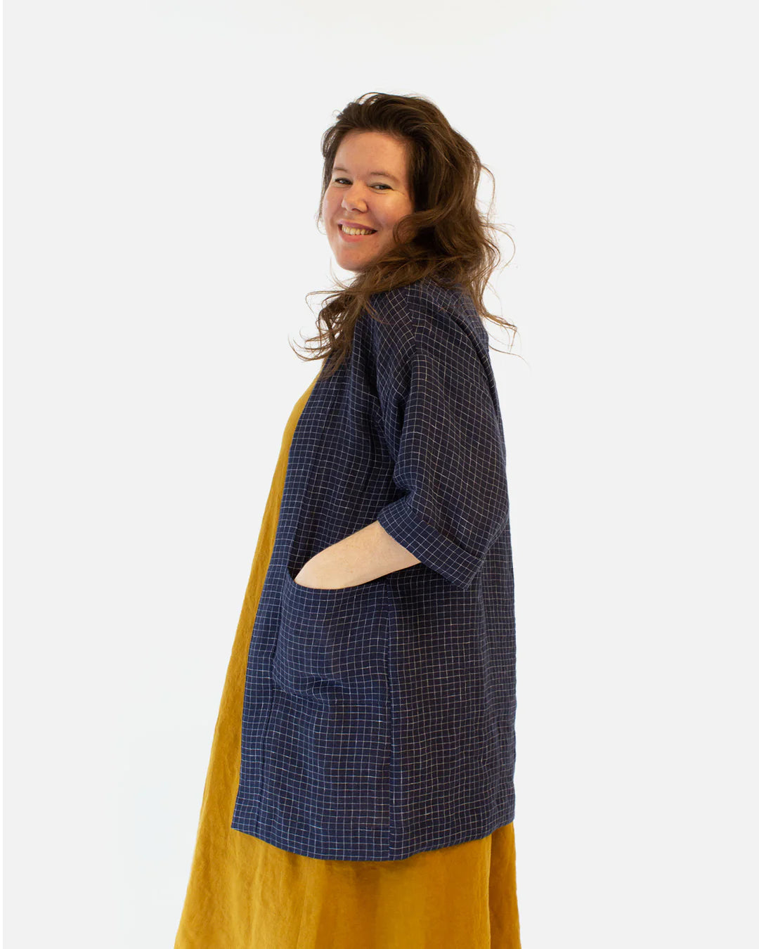 picture from the side of person wearing a moss jacket long view; their hands are in the pockets.