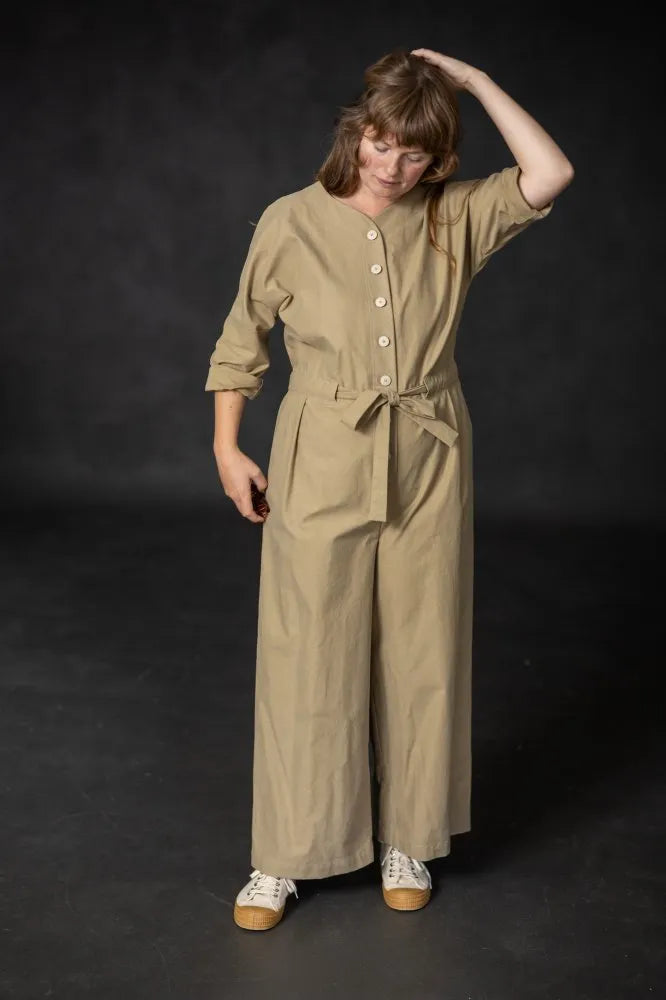 Woman wearing a beige jumpsuit against a black background