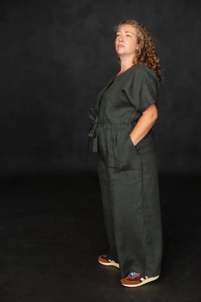 Person wearing a dark green jumpsuit against a black background