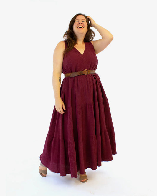 Woman wearing a burgundy dress with a belt on a white background