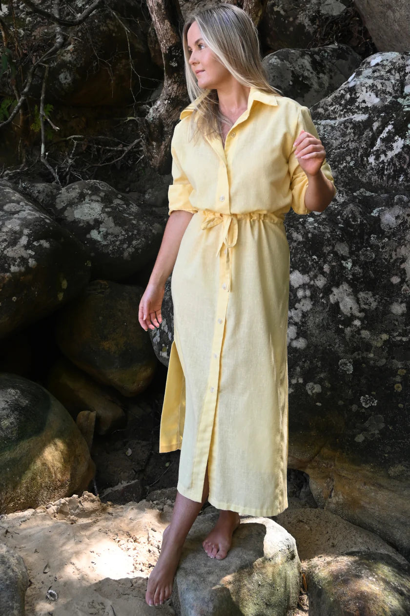 Woman in a yellow dress standing among rocks