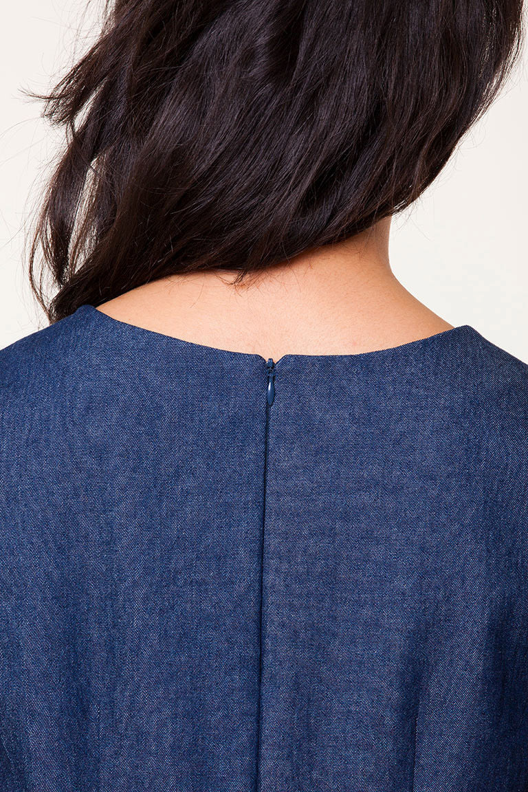 Close-up of a person wearing a blue denim shirt with a plain background