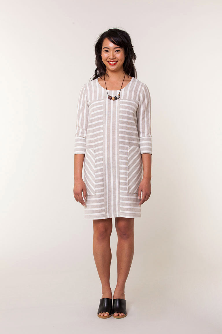 Woman wearing a white and gray striped dress against a plain background
