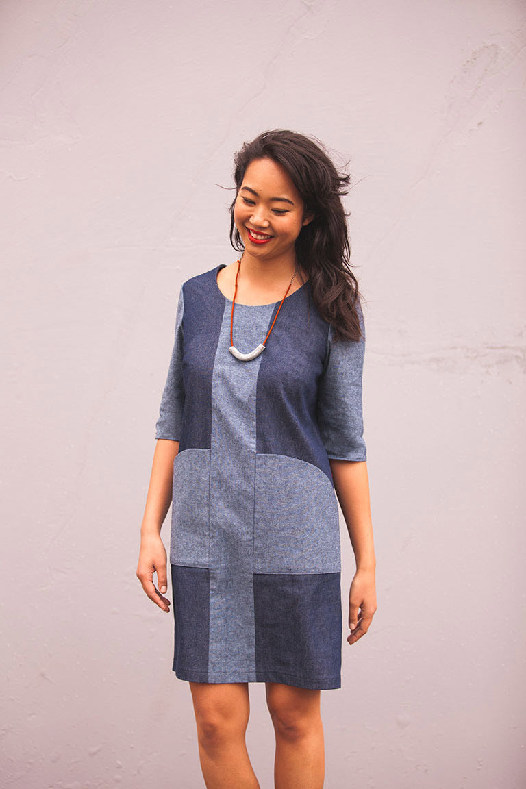 Woman wearing a blue patchwork dress against a plain background