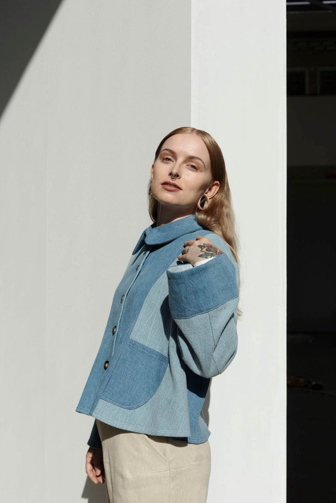 A person wearing a blue denim jacket with a Peter Pan collar, designed by Juliette Gallois, posing against a white background.