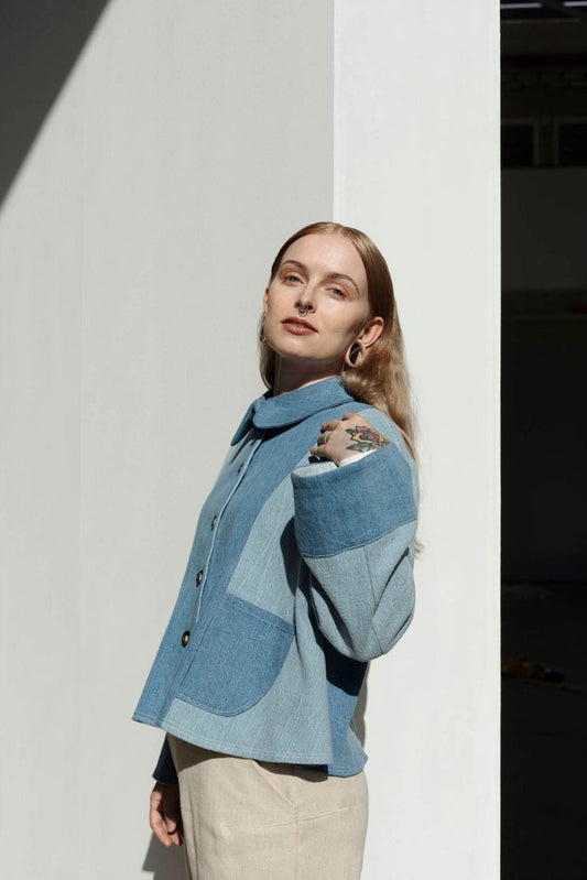 A person wearing a blue denim jacket with a Peter Pan collar, designed by Juliette Gallois, posing against a white background.