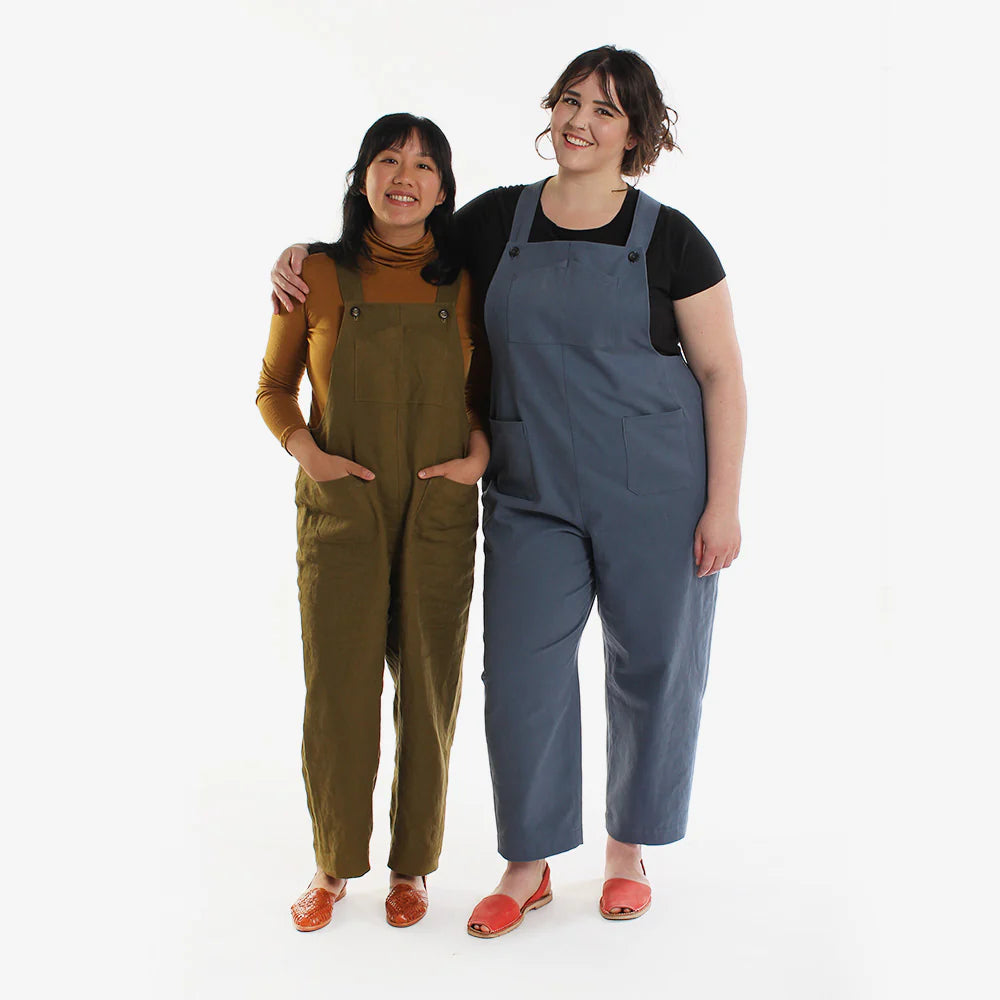 Two people wearing green and blue overalls standing side by side on a white background