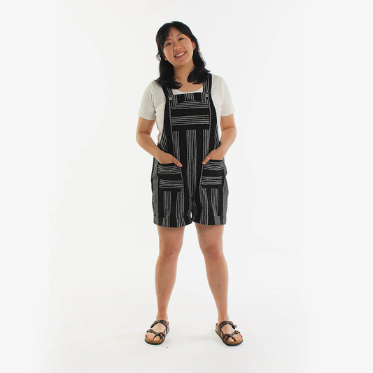 Person wearing black and white striped overalls on a white background