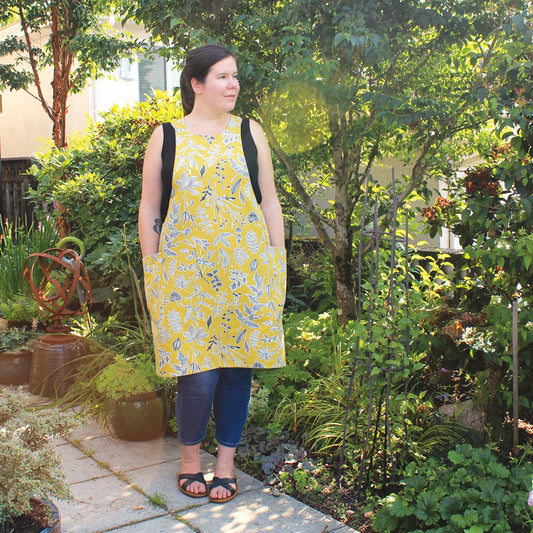 Woman in a yellow floral dress standing in a garden