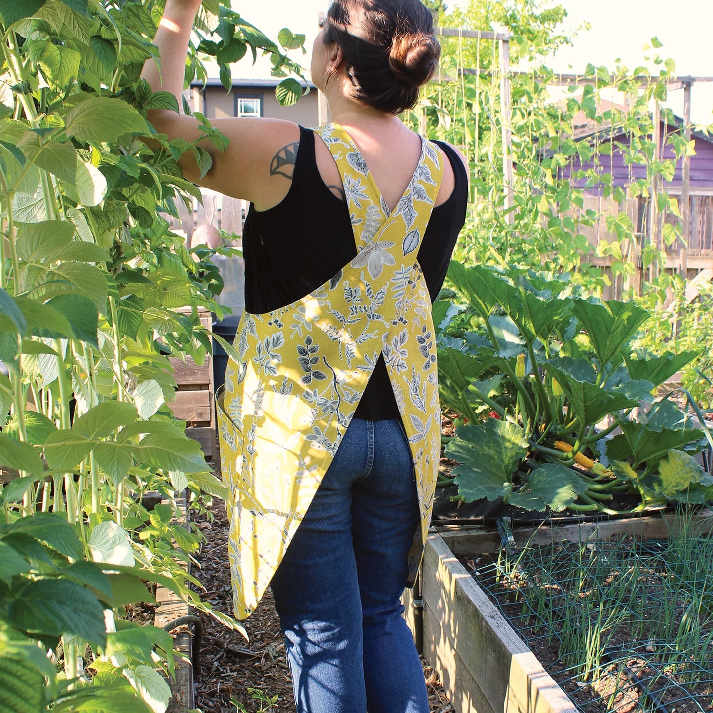 Person wearing a yellow floral apron in a garden
